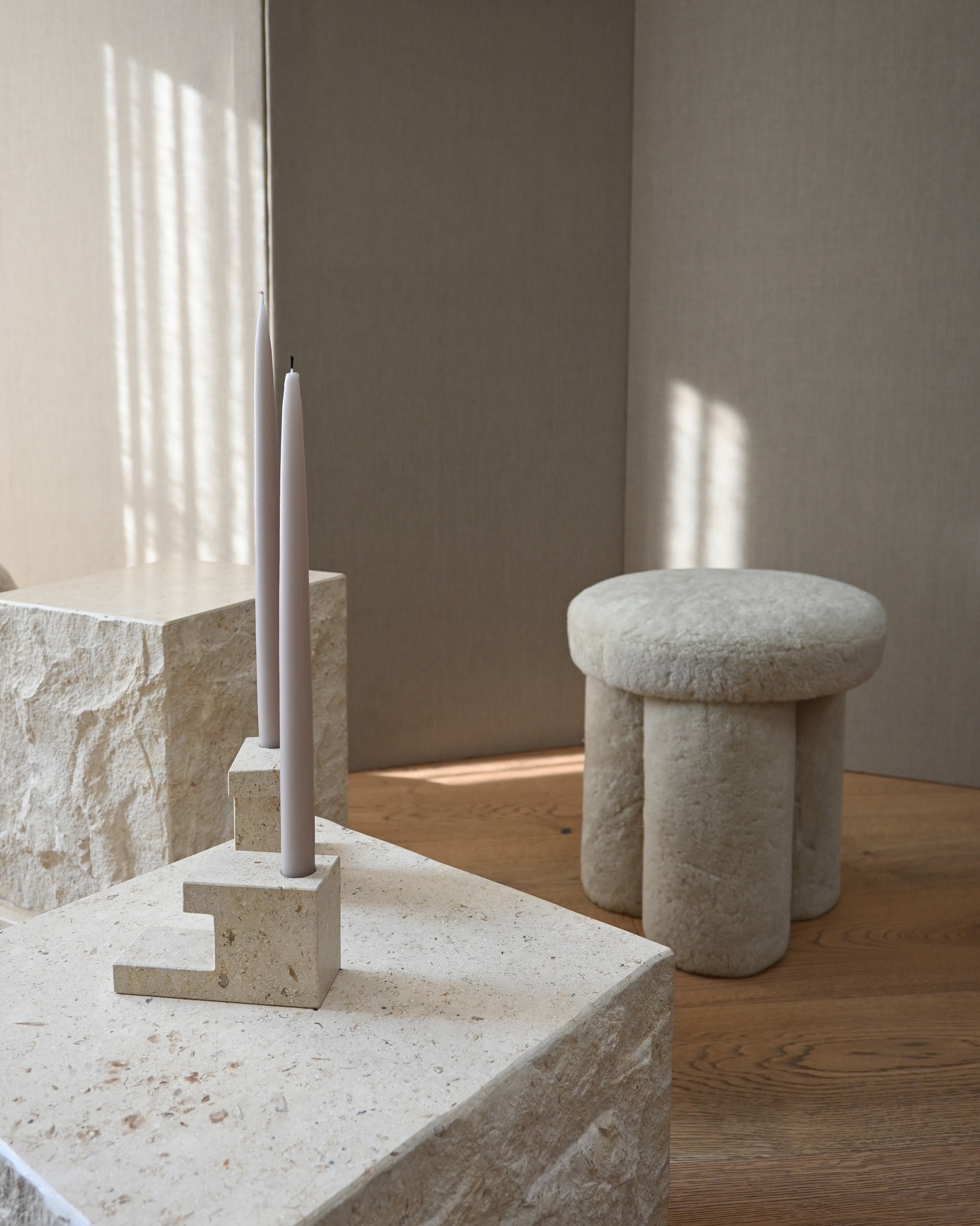 A cozy Scandinavian-style interior featuring a Big Foot Stool and a Toe Chair in white sheepskin, paired with minimalist décor and natural lighting.