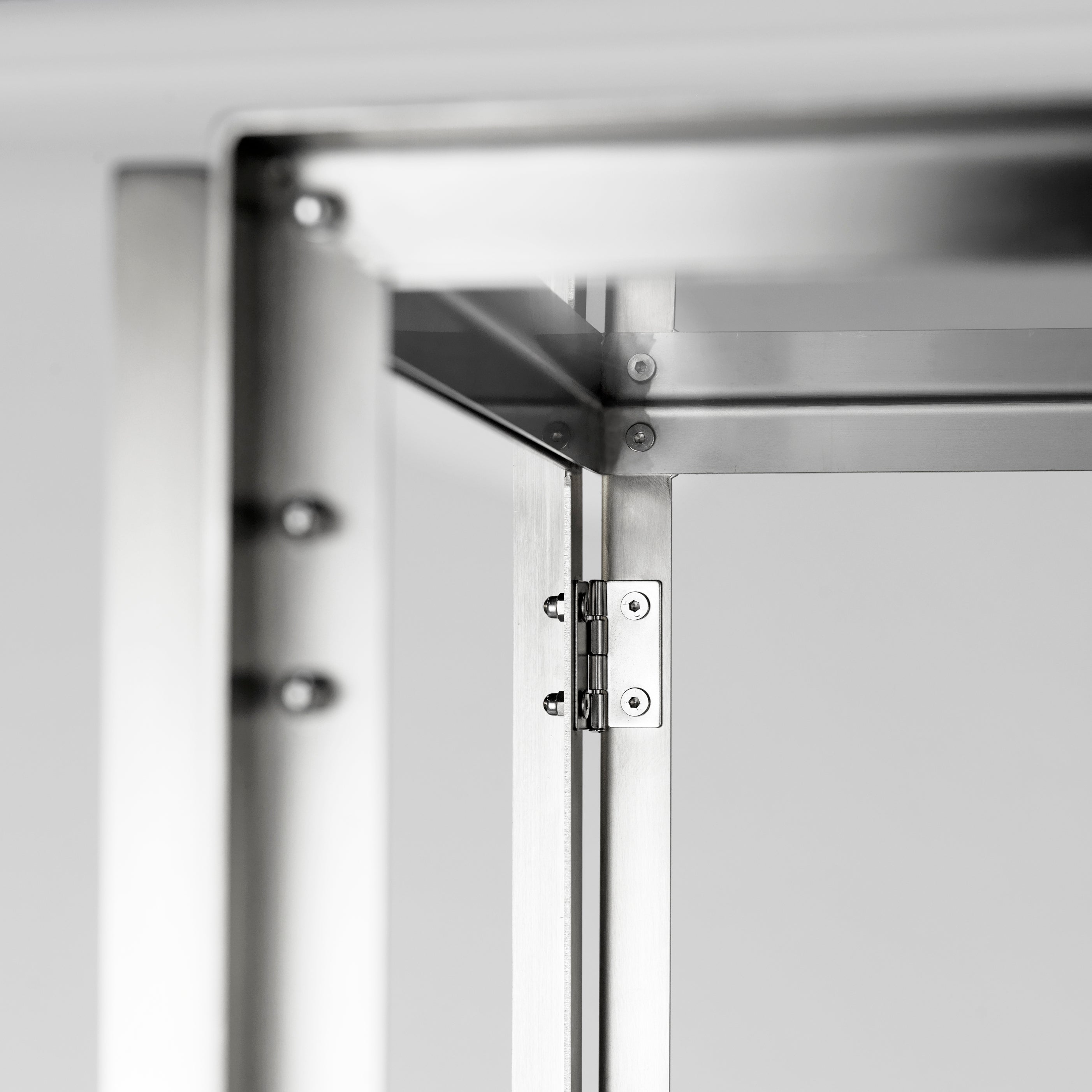 Close-up of a brushed stainless steel foldable shelf hinge, highlighting the precise joint construction and industrial design details