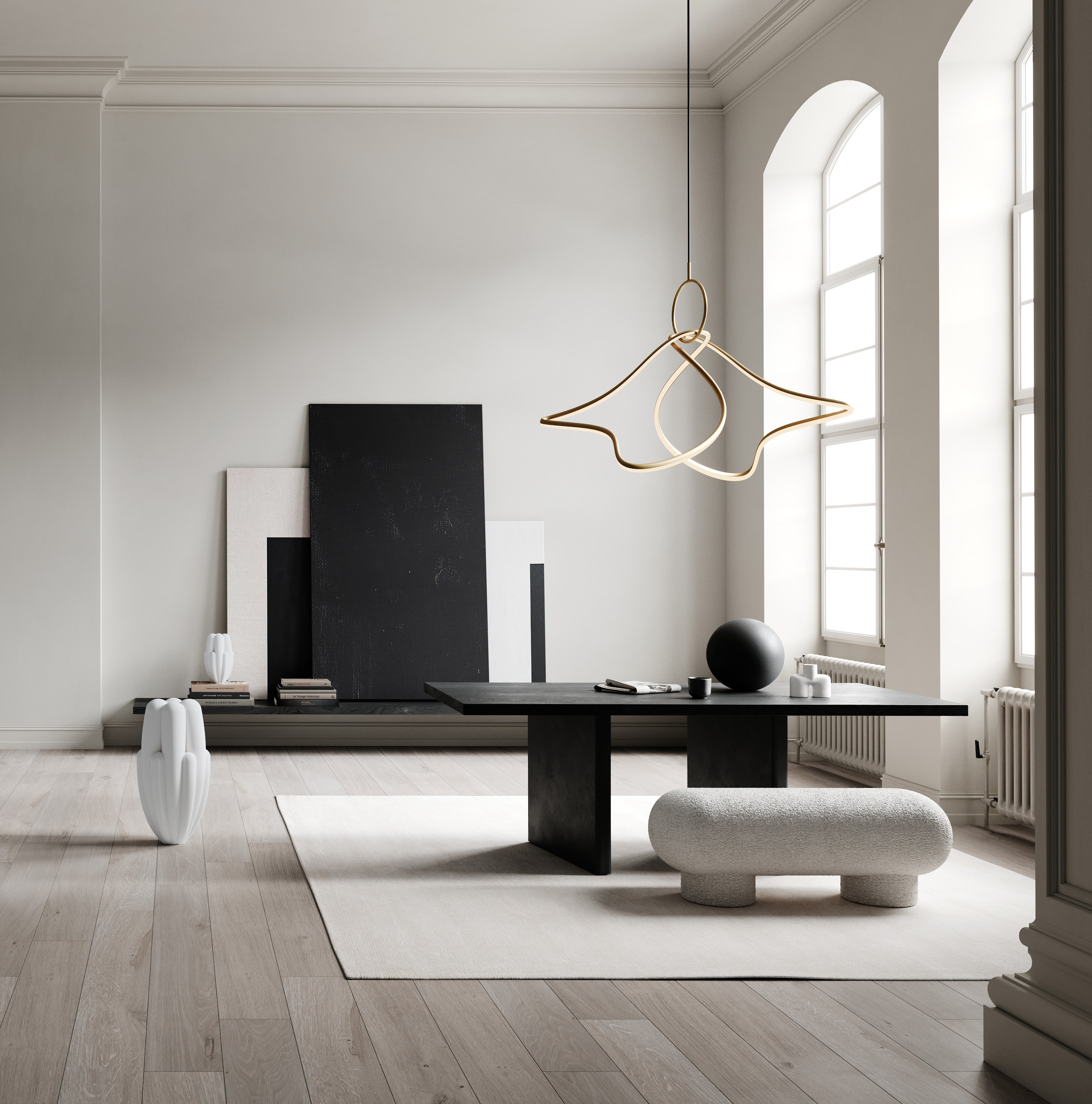 Modern interior setting featuring the Kumo Chandelier Big in brass finish, suspended above a black table with decorative art panels and a white sculptural vase, creating a sophisticated ambiance.